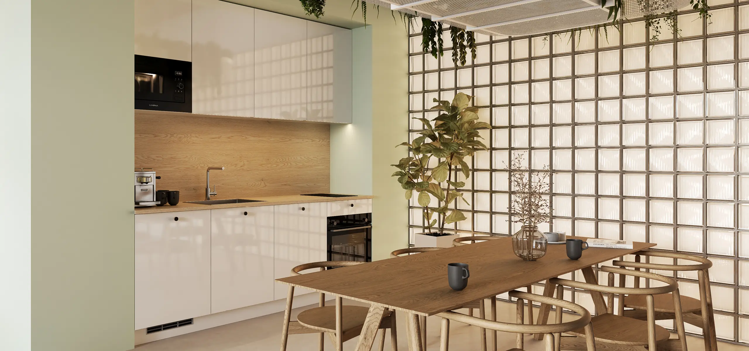 Helle, moderne Wohnküche mit weißen Fronten und Holzarbeitsplatte, Glasbausteinwand, integrierter Mikrowelle/Backofen, Kaffeemaschine, großem Holztisch mit Stühlen und Tassen sowie grünen Zimmerpflanzen.